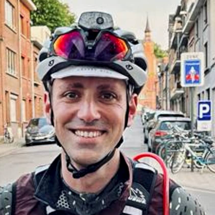 A Cyclist Smiles At The Camera On A City Street