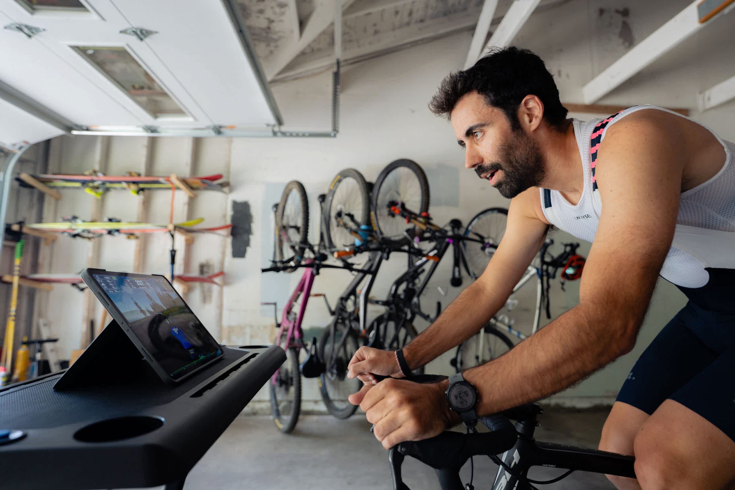Trainingpeaks Virtual Features You’ll Love Image Of A Male Cyclist Riding On An Indoor Trainer In His Garage Using Trainingpeaks Virtual With Bicycles In The Background