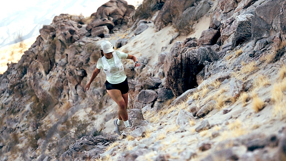 A Woman Trail Running On Rugged Desert Terrain